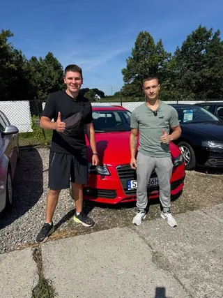 Dwóch klientów przy czerwonym hatchbacku na placu
